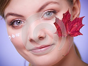 Skin care. Face of young woman girl with red maple leaf.