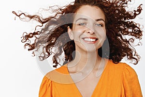 Skin care and haircare cosmetics. Beautiful smiling woman with curly red hair flying in air, floating, smile with white