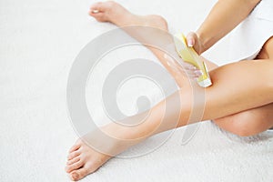 Skin Care and Health. Hair Removal. Fit Young Woman Waxing Her Legs With a Portable Roll-on Depilatory Wax Heater For