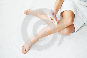 Skin Care and Health. Hair Removal. Fit Young Woman Waxing Her Legs With a Portable Roll-on Depilatory Wax Heater For