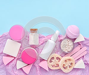 Skin care product - creams, lotion, soap, sponges, bath salt on pink and blue background. Flat lay image with copy space