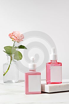 Skin care product set with two dropper bottles with oil or serum on rose oil base on marble podium. Skin care cosmetic