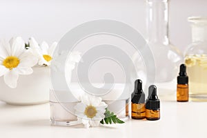 Skin care products, ingredients and laboratory glassware on table.