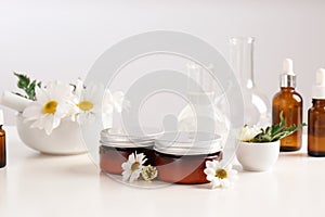 Skin care products, ingredients and laboratory glassware on table.