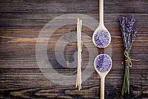 Skin care and relax. Cosmetics and aromatherapy concept. Lavender spa salt on dark wooden background top view copyspace