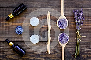 Skin care and relax. Cosmetics and aromatherapy concept. Lavender spa salt and oil on dark wooden background top view