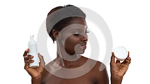 Skin care ritual. Portrait of beautiful young african woman demonstrating cosmetic products while standing in studio