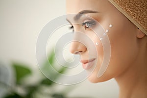 Skin care. Studio shot of beautiful young woman applying moisturizer cream onto her face