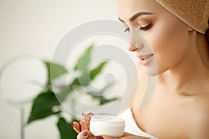 Skin care. Studio shot of beautiful young woman applying moisturizer cream onto her face