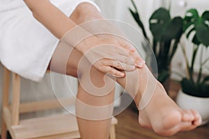 Skin care and wellness concept. Girl hand with moisturizer cream smearing legs for soft skin result. Young woman applying cream on