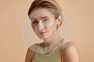 Skin Care Woman Applying Cream on Cheek. Closeup Of Smiling Girl Putting Cream