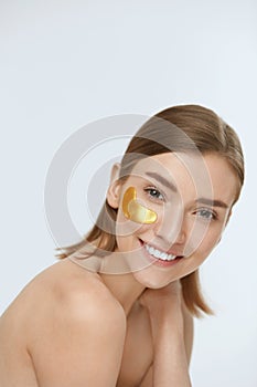 Skin care. Woman face with under eye gold patch, beauty mask