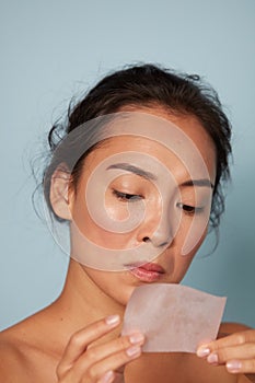 Skin care. Woman holding facial oil blotting paper portrait