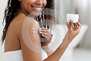 Skin Care. Young African American Female Applying Moisturising Body Lotion After Bath