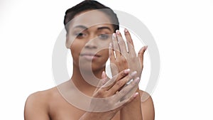 Skin care. Young blurred african american lady applying pampering cream on her hands, looking at camera, focus on palms