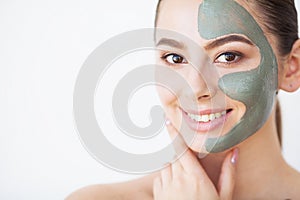 Skin Care. Young woman with cosmetic clay mask holding cucumber