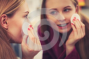 Woman using cotton pad to remove make up