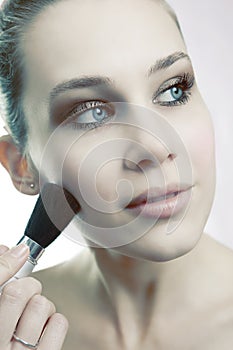 Skin cosmetics - woman using brush on her face