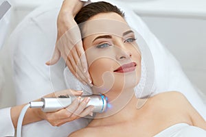 Skin Cosmetology. Woman Doing Blue Light Therapy On Neck