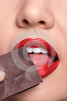 Skin lips closeup licking chocolate, red lipstick