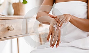 Skin nutrition concept. Unrecognizable black woman applying moisturizing cream to her hands