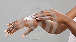 Hands of unrecognizable black woman with applied body lotion. photo