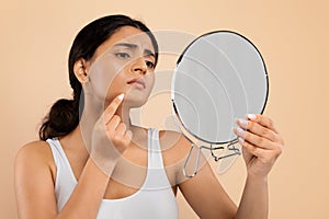 Skin Problems. Indian Woman Holding Mirror And Looking At Pimple On Chin