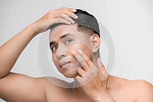 Skin problems. Worried man with a stubble examining his face