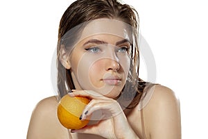 Skincare. Beautiful young woman with orange over white background. Cosmetics and makeup, natural and eco treatment.