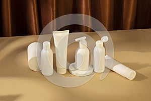 Skincare beauty cosmetic concept. White tube of cream lotion cleanser antioxidant facial oil on brown background