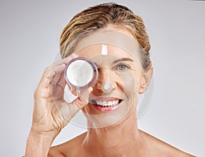 Skincare, beauty and cream on face of mature woman with a smile for luxury spa self care on gray studio background