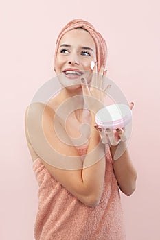 Skincare, cheerful young woman laughing, applying moisturizing cream on face, lotion or mask for skin lifting and anti-aging,
