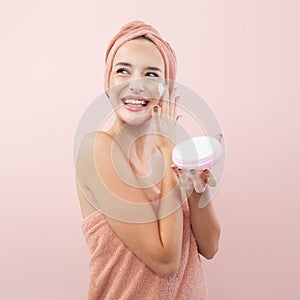 Skincare, cheerful young woman laughing, applying moisturizing cream on face, lotion or mask for skin lifting and anti-aging,