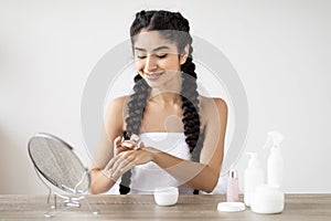 Skincare Cosmetics. Young beautiful indian woman applying hand cream at home