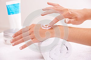 Skincare, cream and hands closeup in spa, touch and massage on towel. Fingers, nails and woman apply lotion in treatment