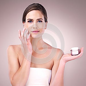 Skincare is essential, makeup is a choice. Studio portrait of an attractive young woman applying moisturizer to her face