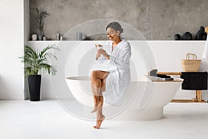 Skincare. Happy Young African American Woman Applying Cream In Bathroom