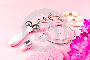 Skincare home spa. Beauty accessories on pink background. Cosmetic ampoules, cocoon of the silkworm, face massager