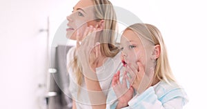 Skincare, mother and daughter home spa day washing their face in bathroom or apply beauty product, lotion or face mask