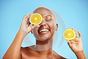 Skincare, orange and smile with a model black woman in studio on blue background for treatment. Face, beauty and fruit