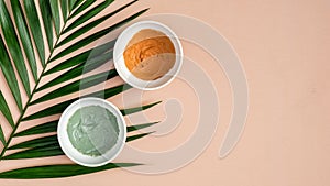Skincare pure clay face masks with tropical palm leaf on peach background. Natural organic SPA cosmetic product, facial skin