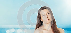 Skincare and sun protection in summer. Portrait of a beautiful young suntanned woman, blue sea and sky on background