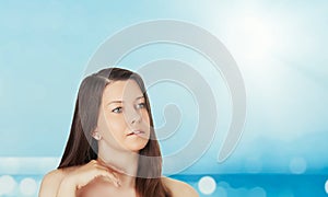 Skincare and sun protection in summer. Portrait of a beautiful young suntanned woman, blue sea and sky on background photo