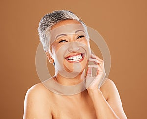 Skincare, wellness and senior woman with makeup for face with a smile and happy against a brown studio background