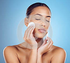 Skincare, woman with cottonwool on face and eyes closed removing makeup or dirt with luxury skin product in studio