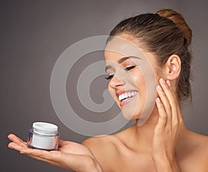 Skincares secret weapon. Portrait of a beautiful young model holding up a tub of skin cream in studio.