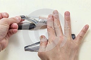 Skinning fresh raw sardine fish by hands in the kitchen