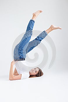 skinny caucasian pretty female lying on floor at white studio with legs raised