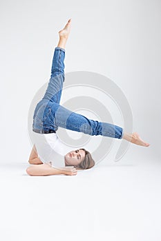 skinny caucasian pretty female lying on floor at white studio with legs raised