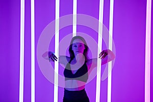 Skinny fashion model wear black erotic lingerie in colorful bright neon uv purple lights posing in studio. Close up.